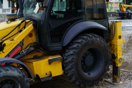 A construction vehicle works diligently on a busy urban site, equipped with large tires and tools...