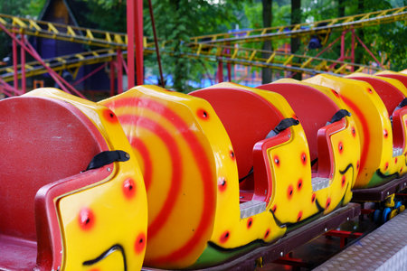 Brightly colored roller coaster seats are lined up in an amusement park, ready for visitors. The...