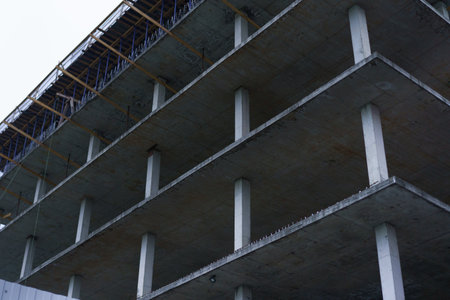 A large construction site displays a concrete building under development. Scaffolding surrounds the...