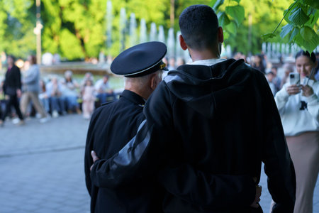 Two individuals share a heartfelt moment in a park, enjoying a sunny afternoon. People are gathered...