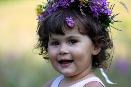 portrait of a happy laughing little girl with flower garlandの写真素材
