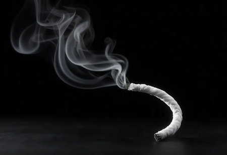 A captivating image of a cigarette creating delicate smoke swirls against a dark background. The gentle and fluid motion evokes feelings of tranquility and serenity.の素材