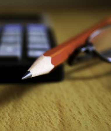 Close-up shot of a sharp pencil with calculator and a spectacle の写真素材