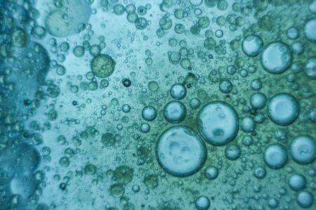 Blue oil bubbles floating on water surface