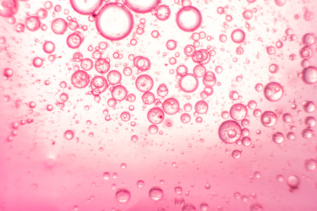 Pink oil bubble floating on surface of water