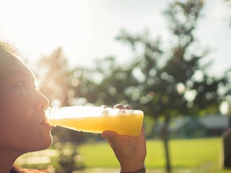 asian women drinking bottle of orange juice.の写真素材