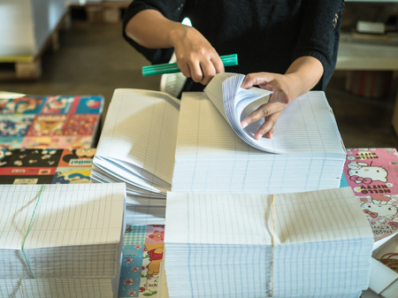 Asian women fold a piece of paper to ready to make a books in book factory.