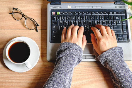 A cup of coffee on a woman's work table.の写真素材