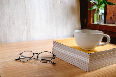 Coffee cup and book with glasses on the table