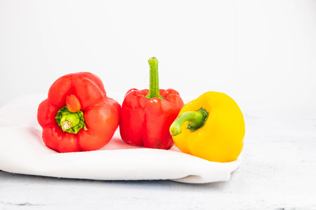 Fresh red and yellow bell peppers on a white woodenの写真素材