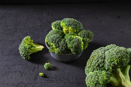 Broccoli in a bowl on a black background.