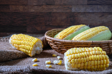 Fresh corn in basket on  on wooden tableの写真素材