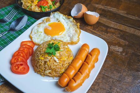 American fried rice served with fried eggs and sausages on the tableの写真素材