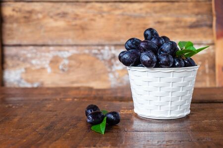 Black grapes in a basket on a wooden tableの写真素材