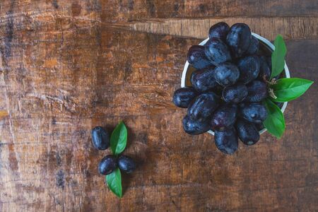 Black grapes in a basket on a wooden tableの写真素材