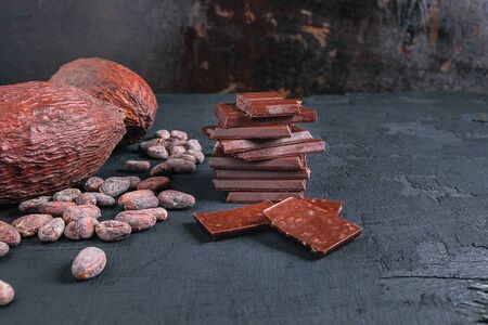 Dark chocolate pieces  and cocoa beans on table