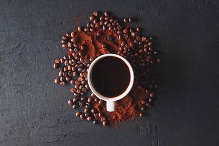 Hot coffee with coffee powder and coffee beans on a black backgroundの写真素材