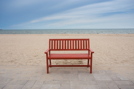Alone wooden red beach chair sitting on the sand with sea.の写真素材