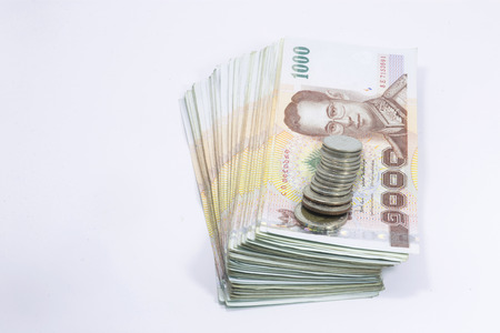 One thousand baht Thailand banknote and coins on a white background.