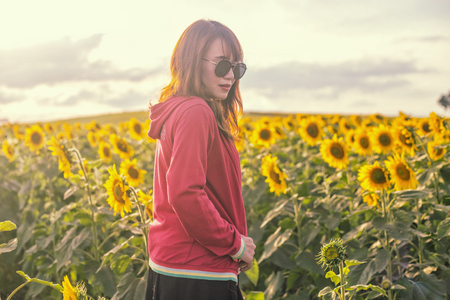 A portrait of beautiful asian woman on blooming sunflower field in summerの写真素材