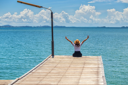 Asian woman sitting happy on the Wooden bridge looking at the sea at Khao Laem Ya Mu Ko Samet National Park , Rayong , Thailandの写真素材