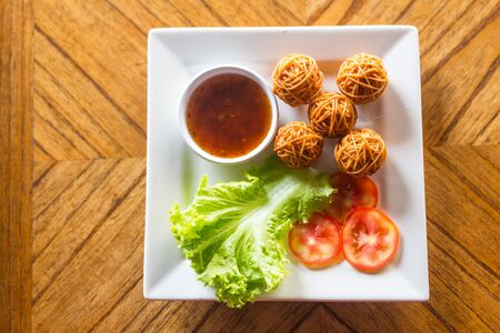 Deep Fried Wrapped Pork with Chinese Noodle and vegetables on white plate in thai restaurantの写真素材