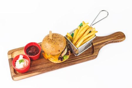 homemade burger with cheese and french fries in basket with ketchup and sauce on white backgroundの写真素材