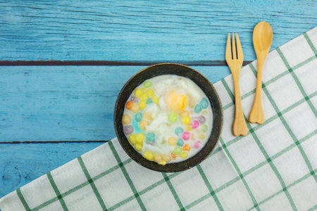 Thai dessert Bua Loy on a blue wood background with wooden cutleryの写真素材
