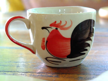 Ceramic coffee cup with chicken pattern on brown wooden tableの写真素材