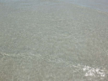 The sea water is clear, can see the sand and there is a shadow from the sun.の写真素材