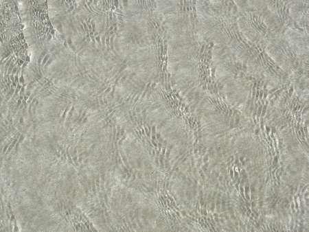 The sea water is clear, can see the sand and there is a shadow from the sun.の写真素材