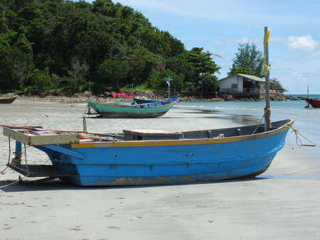 Blue and green local fishing boats moored on the shorelineの写真素材