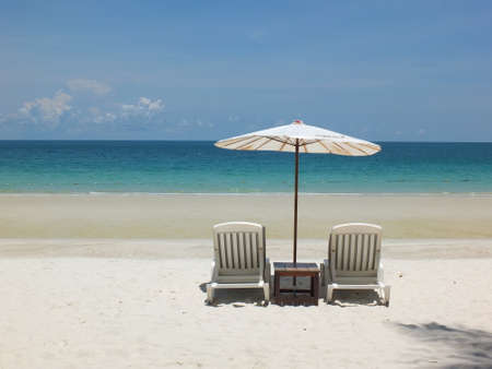 White beach bed with white umbrellas rests on white sand, sea front and blue sky.の写真素材