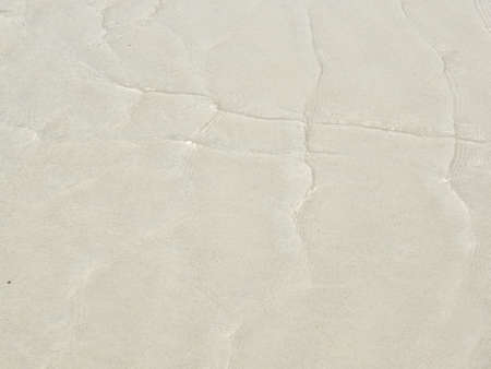 Clear water on the beach with brown sand.の写真素材