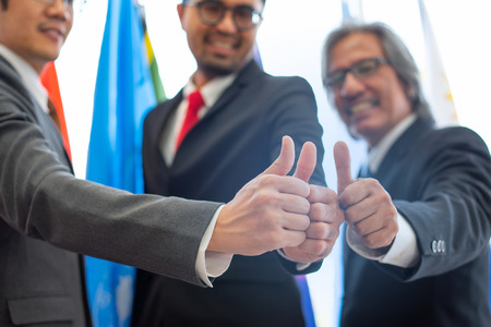 Three business men show thumbs up during international conferenceの写真素材