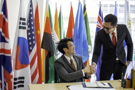 Couple of business men or politicians look happy and shake hand to show the cooperation of their work during international conferenceの写真素材