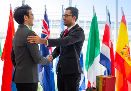 Couple of business men or politicians look happy and shake hand to show the cooperation of their work during international conferenceの写真素材
