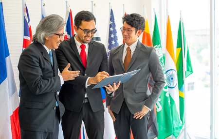 Group of business or political men look happy during the discussion of their work and they stand in front of various international flagsの写真素材
