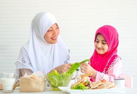 Muslim mother discuss and teach about vegetable for food to her little girl with white backgroundの写真素材
