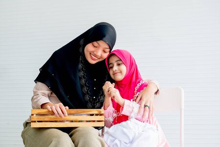 Muslim mother and her daughter are enjoin with cosmetic activity together in the room with white background and copy space.の写真素材