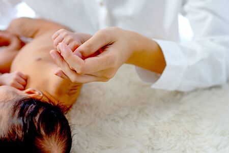 Soft blur and close up view mother hold kid's hand with concept of mum bond of love to baby.