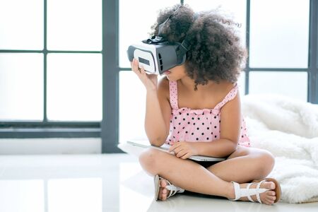 One African mixed race girl enjoy with VR glasses and also hold laptop in the room with day light.の写真素材