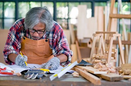 Old craftsman measure and work with wood products and also use several tools for helping of work.の写真素材