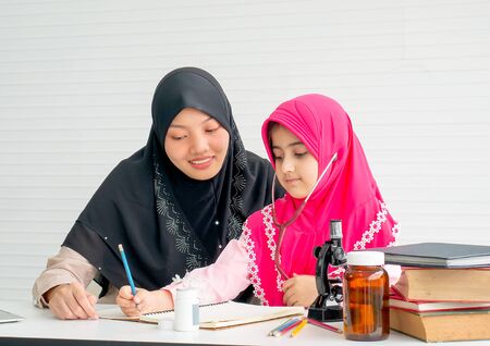 Muslim mother teach her daughter to learn about science and health in the room with white curtain.の写真素材