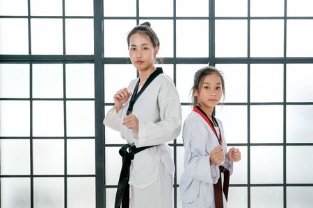 Young teacher of taekwondo and her student is acting of basic posture with white background and pattern.の写真素材