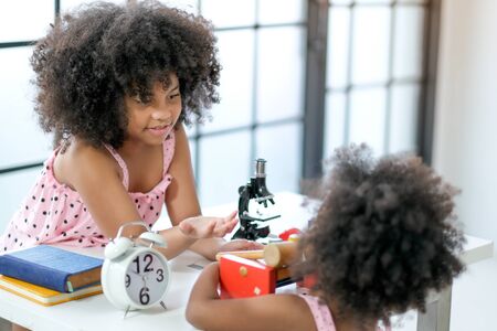Older sister African girl play with her younger sister with different decorations in the living room with day light.の写真素材