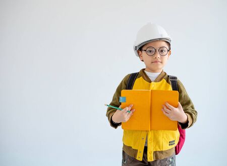 Portrait of Asian yellow coat and white engineer helmet hold yellow notebook and look forward with...