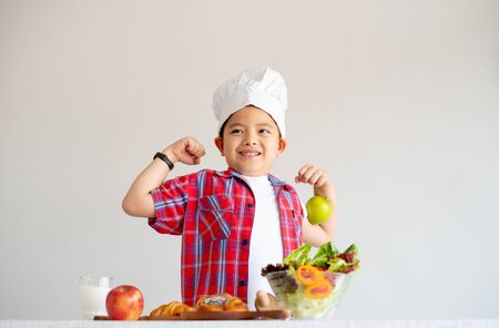 Asian red shirt little boy show action of feel stronger with various types of vegetable and fruits with healthy food concept for children.の写真素材