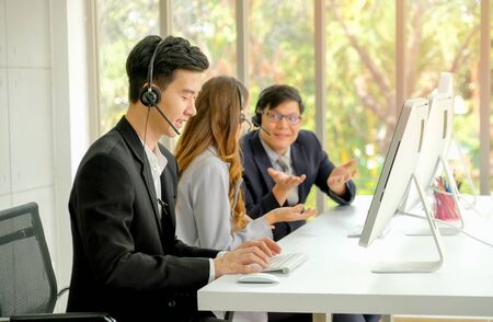 Young man work as operator with diligent habit while his co-workers talking together during working time.の写真素材