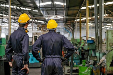 Soft blur image of the back of two technician men stand and look to various type of machine in factory.の写真素材